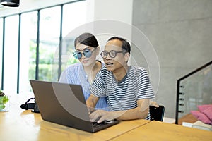 Asian man and woman working on computer laptop at home living room