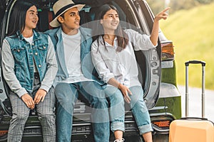 Asian man and women relaxing in back of car trunk during travel in summer. Transportation and people lifestyles concept. Group of