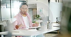 Asian man, working and eat apple in office for lunch time snack, planning tech strategy on pc and checking phone