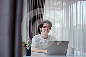 Asian man working from home with laptop computer self isolation from society to reduce risk