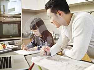 Asian man working at home while taking care of daughter