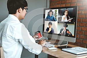 Asian man working from home use Smart working and video conference online meeting with Asian team using laptop and tablet online