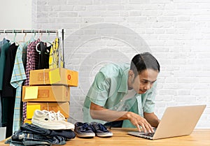 Asian man working laptop computer selling online