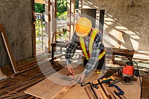 Asian man works in a carpentry shop. Carpenter working with equipment on wooden table at construction site