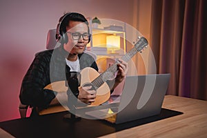 Asian man youtuber live streaming perfomance playing guitar and sing a song. Asian man teaching guitar and singing online.