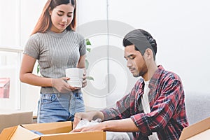 Asian married couple start new family life concept. Woman and man unpacking messy boxes after moving in new house together