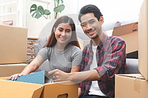 Asian married couple start new family life concept. Woman and man unpacking messy boxes after moving in new house together