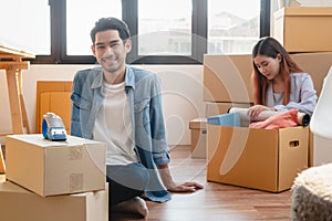 Asian married couple start new family life concept. Woman and man unpacking messy boxes after moving in new house together