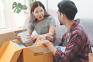 Asian married couple start new family life concept. Woman and man unpacking messy boxes after moving in new house together