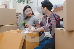 Asian married couple start new family life concept. Woman and man unpacking messy boxes after moving in new house together