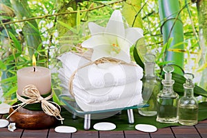 Asian massage oil with candle, towels and lily