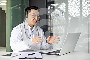 Asian mature doctor conducting an online consultation via laptop