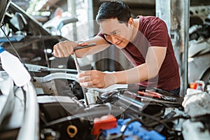 asian mechanic man using T socket repairing a car engine