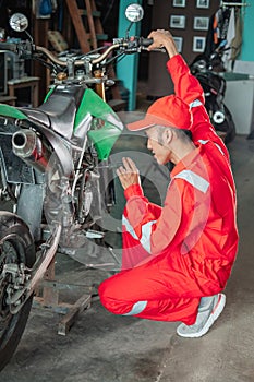 Asian mechanic setting up the carburetor using a screwdriver next to the dirt bike