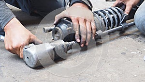 Asian mechanic using an air gun to unscrew of shock absorber replacement, Service industry of transportation