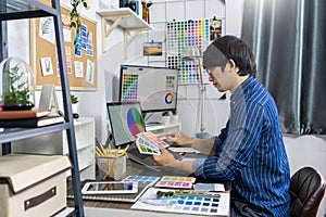 Asian men Architect or graphic designer designing a layout selection swatch samples for coloring screen graphics at work for