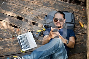 Asian men backpacks and traveler working on computer laptop at outdoor nature and He is relaxing and enjoying on travel