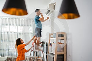 asian man climbing up stairs to fixing airconditioner photo