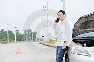 Asian men driver check for damage after a car accident before taking pictures and sending insurance. Online car accident insurance