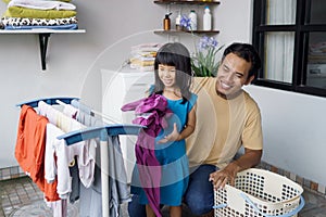 father householder and child daughter in laundry drying clothes photo