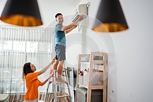 asian man install airconditioner with partner photo