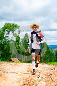 Asian men`s trail runners wearing sportswear and equipment. Practicing running and on a high mountain, running on a dirt path On