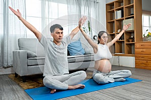 Asian men and women are Husband and wife with pregnant wives wearing open belly shirts. sitting in a yoga