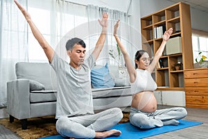 Asian men and women are Husband and wife with pregnant wives wearing open belly shirts. sitting in a yoga pose