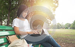 Asian mid aged woman using laptop in park