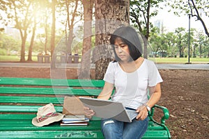 Asian mid aged woman using laptop in park