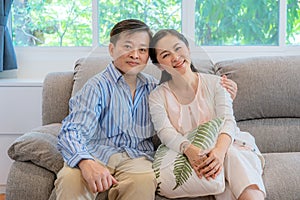 Asian middle-aged couples sit and relax on the sofa in the living room