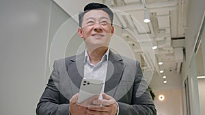 Asian middle-aged man businessman entrepreneur use phone mobile modern technology win business opportunity offer happy
