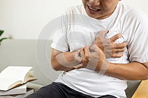 Asian middle-aged man clutching chest pain,difficulty breathing suffer from heart attack,angina pectoris disease,heart and