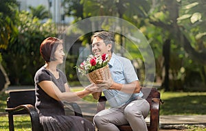 Asian middle-aged man gives a rose to his wife in valentine day