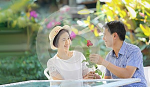 Asian middle-aged man gives a rose to his wife in valentine day