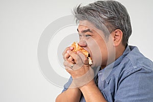 Asian Middle aged man holds and eating a hamburger deliciously Concept of binge eating disorder BED and Relaxing with Eating