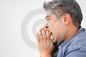 Asian Middle aged man holds and eating a hamburger deliciously Concept of binge eating disorder BED and Relaxing with Eating