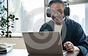 Asian middle aged man sitting at home working on video call. Work from home concept.