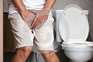 Asian middle aged man suffering from dysuria,acute cystitis, urinary tract infection,people patient holding crotch in toilet,