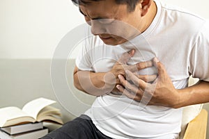 Asian middle-aged man touching his chest,suffocation and chest pain and tightness,sick male patient with heart or asthma attack, photo
