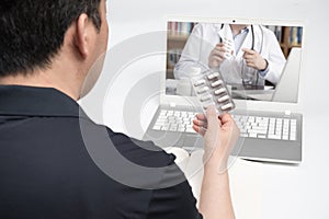An Asian middle-aged man using a laptop to consult a doctor on telemedicine