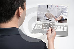 An Asian middle-aged man using a laptop to consult a doctor on telemedicine