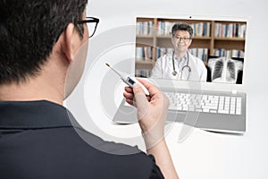 An Asian middle-aged man using a laptop to consult a doctor on telemedicine