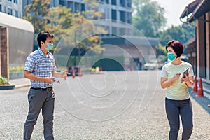 Asian middle aged people wearing mask and keep social distancing to avoid the spread of COVID-19