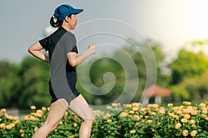 Asian middle-aged woman wearing a black dress, blue hat, running stretching in park near to lake. Get the sun light in the morning