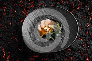 Asian miso soup ,soy sauce, greens and shrimps prawn. On a black stone background