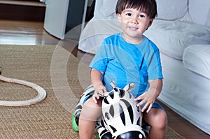 Asian, mixed race toddler boy sitting on a zebra rideon