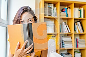 Mixed race woman reading book in library, education and lifestyle concept