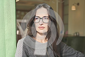 asian mixed race woman sitting in a cafe and looking aside. young beautiful businesswoman wearing glasses thinking alone