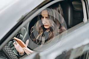 asian or mixed race woman sitting in a car and texting to a friend on a smartphone. car driving safety. communication